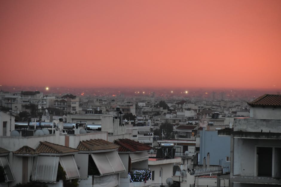 Captivating view of Athens cityscape under a vibrant red sunset sky, showcasing urban architecture.