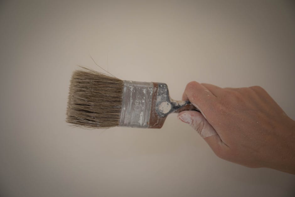 Hand gripping a paintbrush, ready for painting. Ideal for artistic themes.