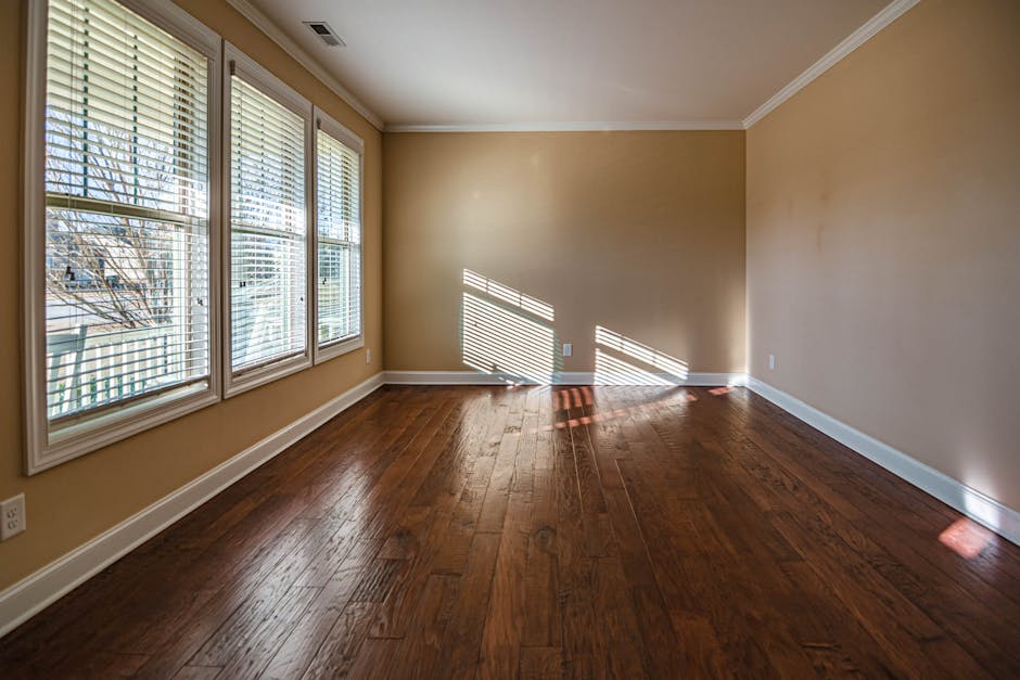 Sunlit empty room with hardwood floors and large windows, ideal for home staging.