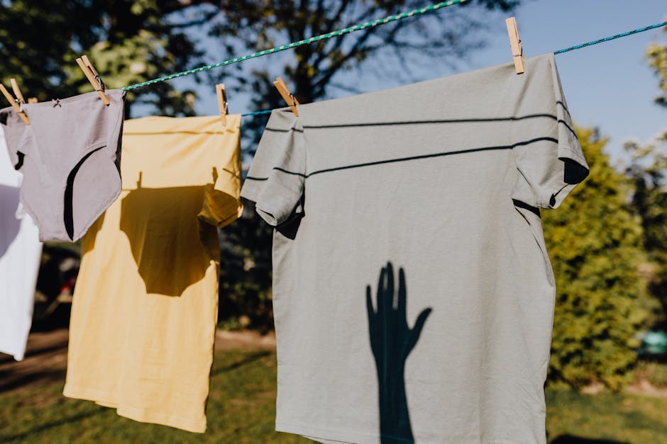 Clean washed clothes hanging on rope with clothespins outdoors on sunny summer weather