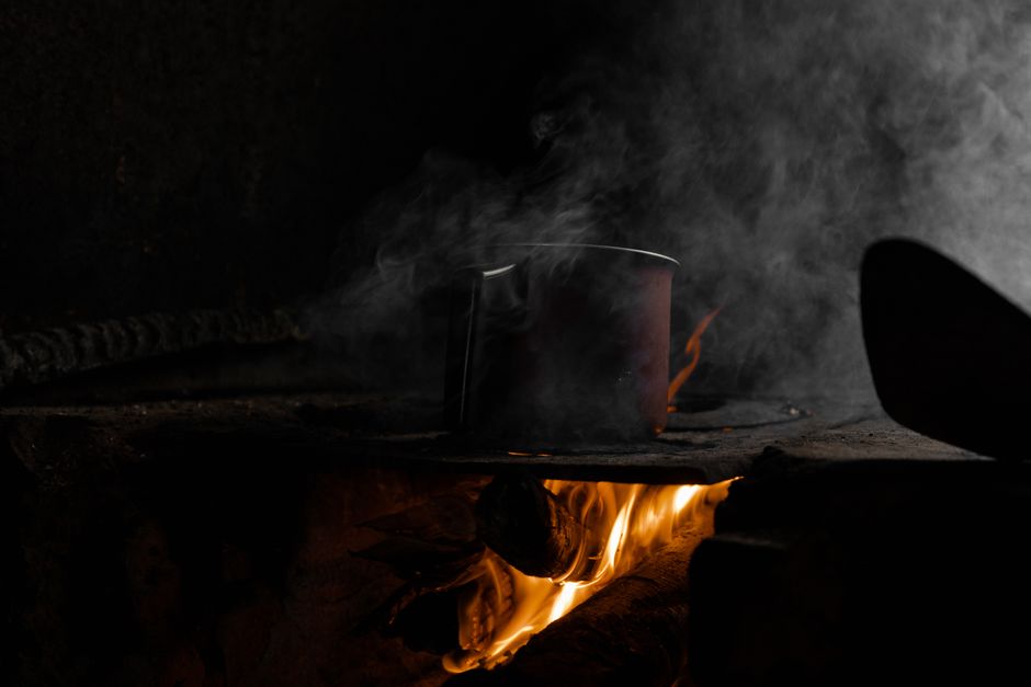 A pot on a rustic wood-burning stove with fire and smoke in Natividade da Serra, Brazil.