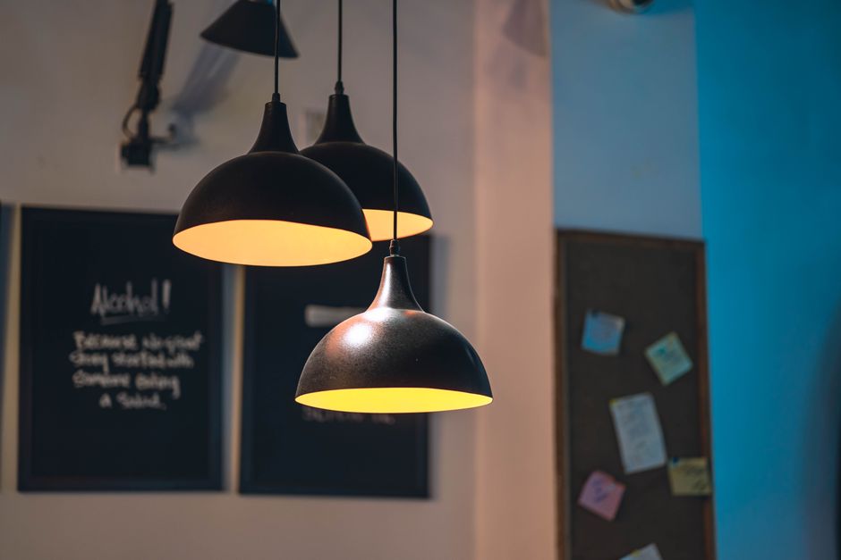A close-up of illuminated hanging lamps in a cozy, modern café setting with blurred background.