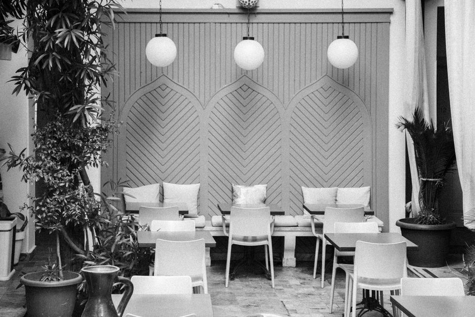 Chic outdoor seating at a stylish cafe with plants and decorative lighting, in black and white.