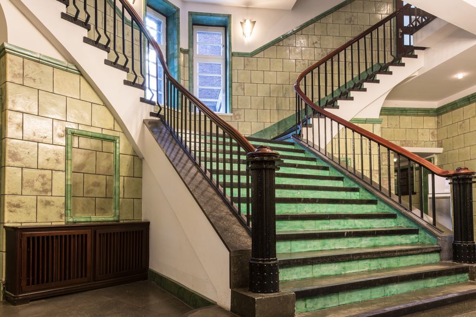 Elegant green-tiled staircase in historic Hamburg architecture, showcasing art deco charm.