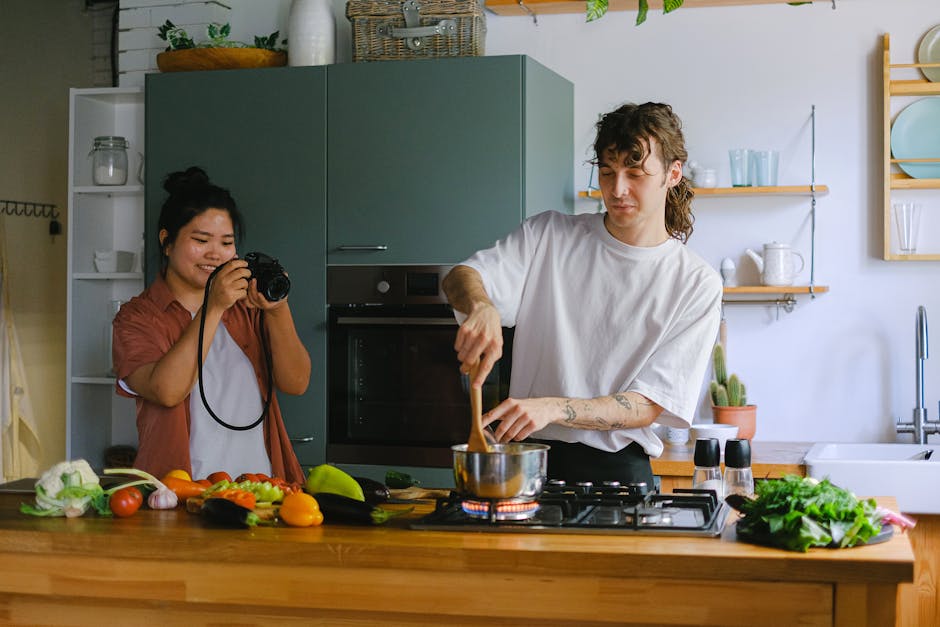 A couple engaged in cooking and photography in a modern kitchen setting.