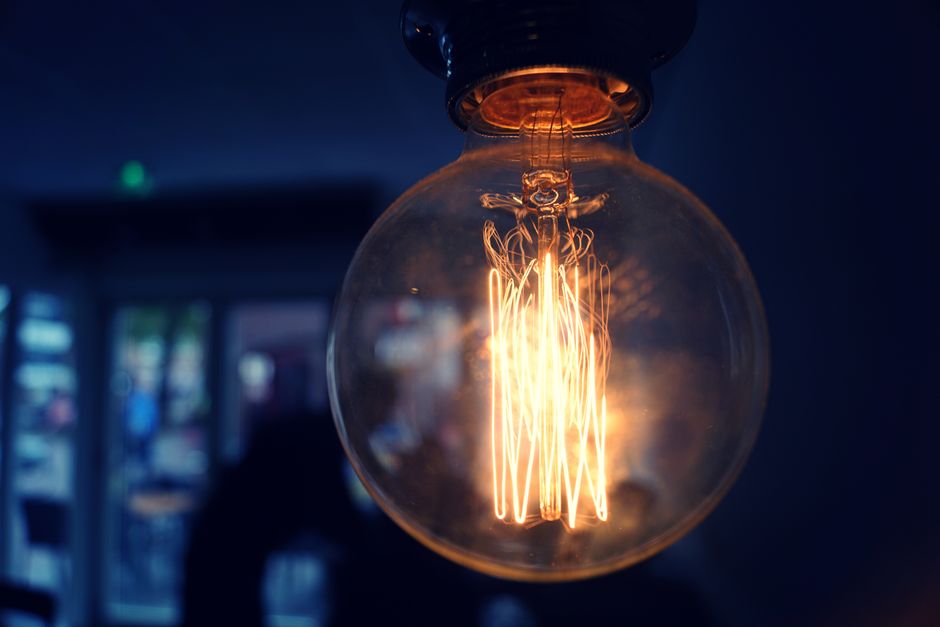 Close-up of a glowing vintage Edison light bulb in a dim indoor setting.