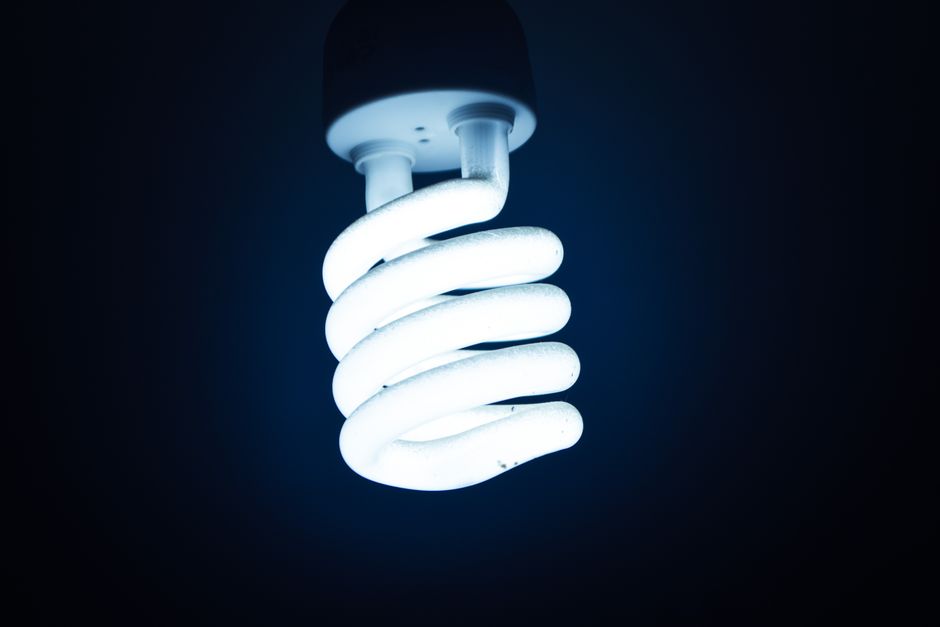 Close-up of a glowing spiral energy-saving bulb against a dark backdrop, emphasizing sustainable energy.